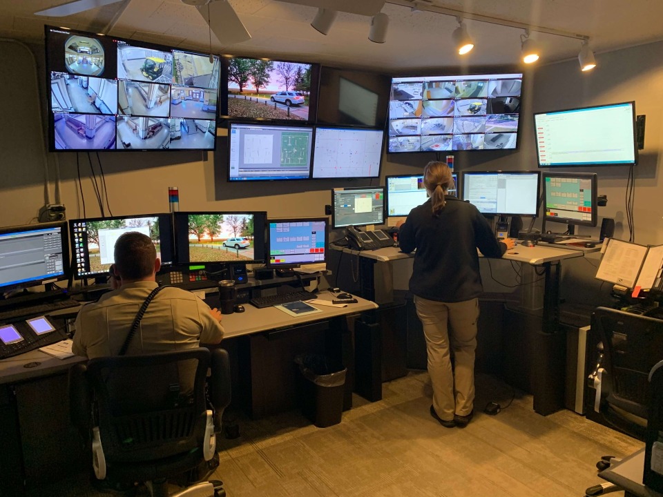 Two Chickasaw County Sheriff's communication/dispatch team members at work in the communications center surrounded by many screens.